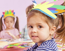 Girl in handmade headwear glue paper to cardboard early head start