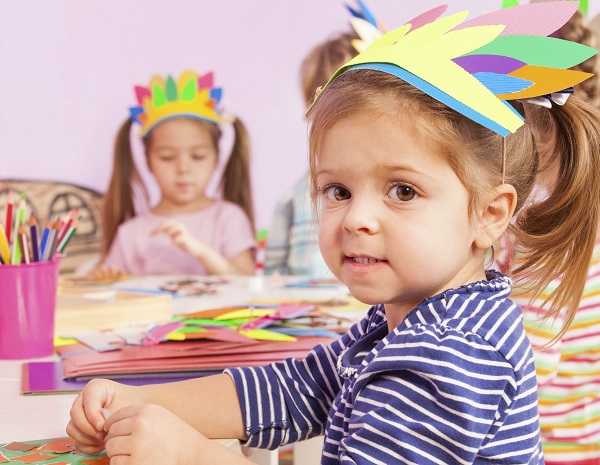 Girl in handmade headwear glue paper to cardboard mvcaa head start program