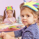 Girl in handmade headwear glue paper to cardboard